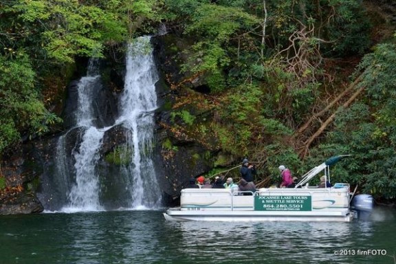 a person riding on the back of a boat next to a waterfall