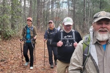 a group of people standing in a wooded area