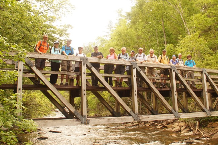a group of people riding on top of a wooden fence
