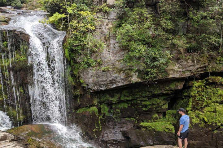 a man standing next to a waterfall