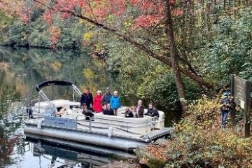 a person riding on the back of a boat next to a tree