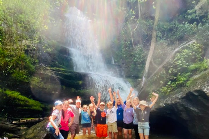 a group of people standing next to a waterfall