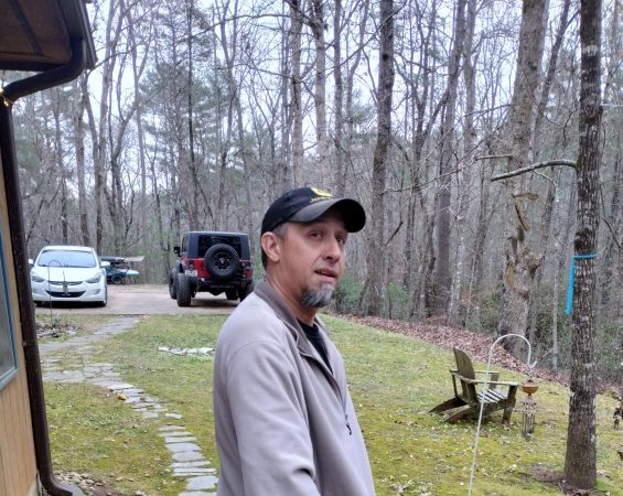 a man standing next to a fence