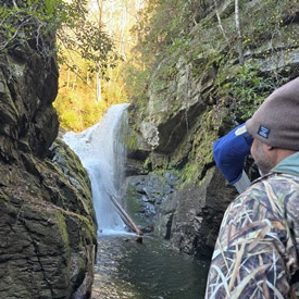 a man standing next to a waterfall