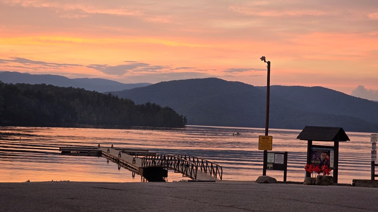 a sunset over a body of water with a mountain in the background