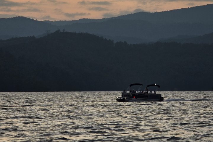 Boat on a lake during sunset with silhouetted hills in the background.