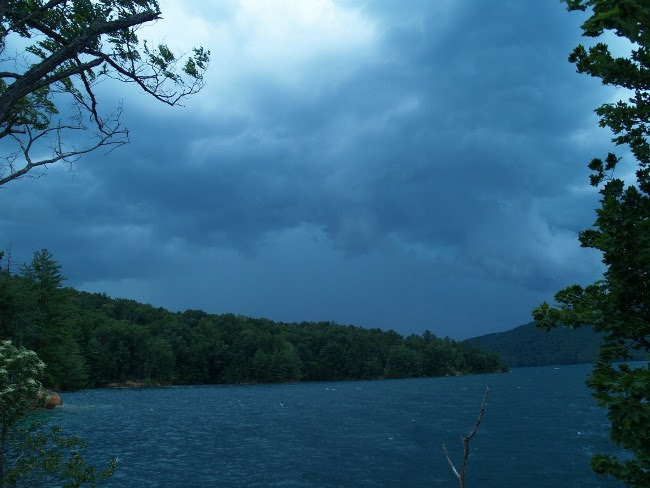 Lake with dark stormy clouds and surrounding trees.