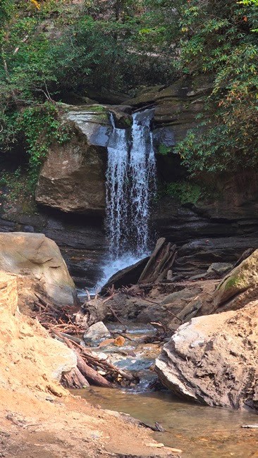 Small waterfall surrounded by rocks and trees in a forest setting.